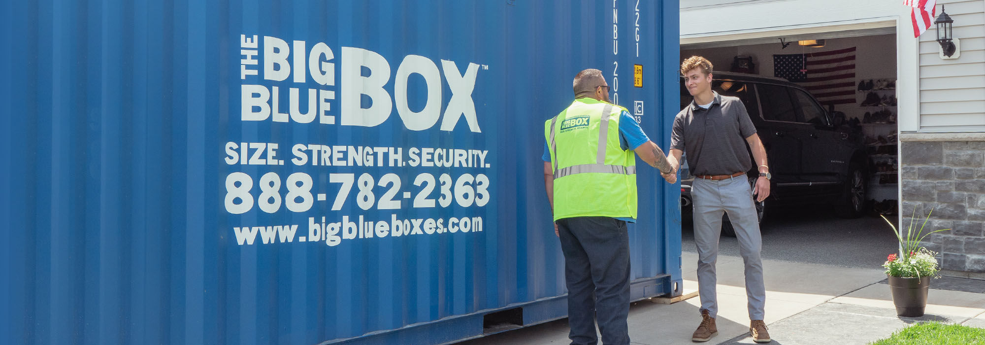 Two men shaking hands in front of a storage container