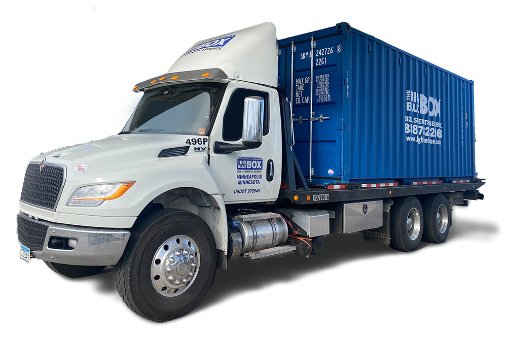 A white truck with a big blue box on the bed