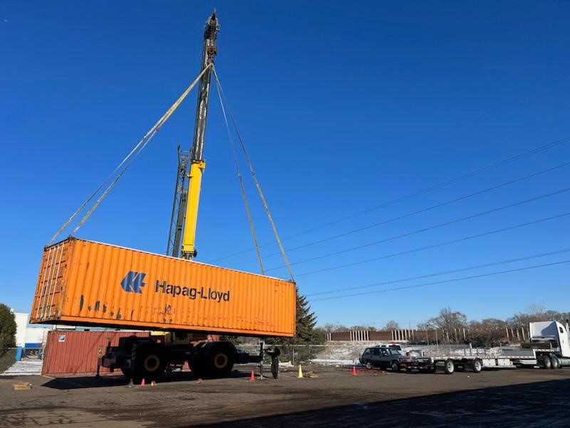 An orange storage container being lifted on a truck