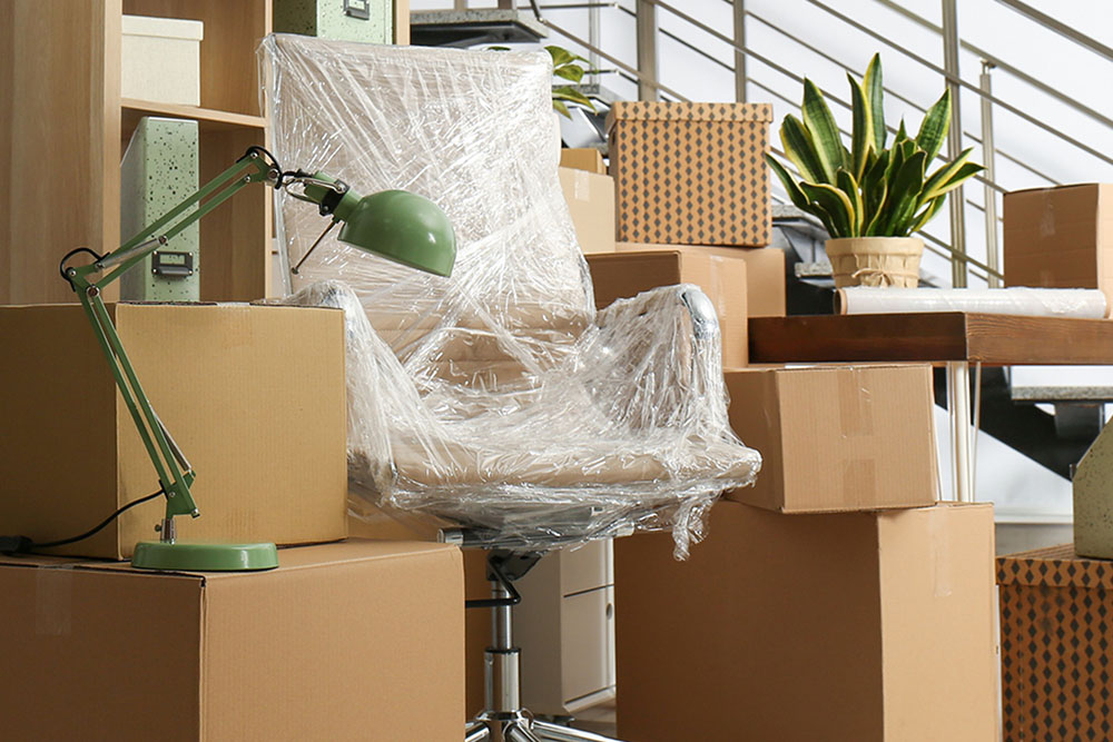 A desk chair wrapped in plastic around moving boxes