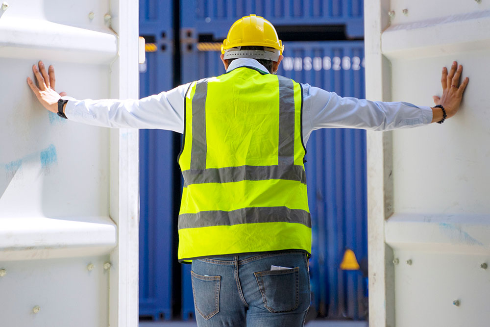 A construction worker in between two white storage containers.