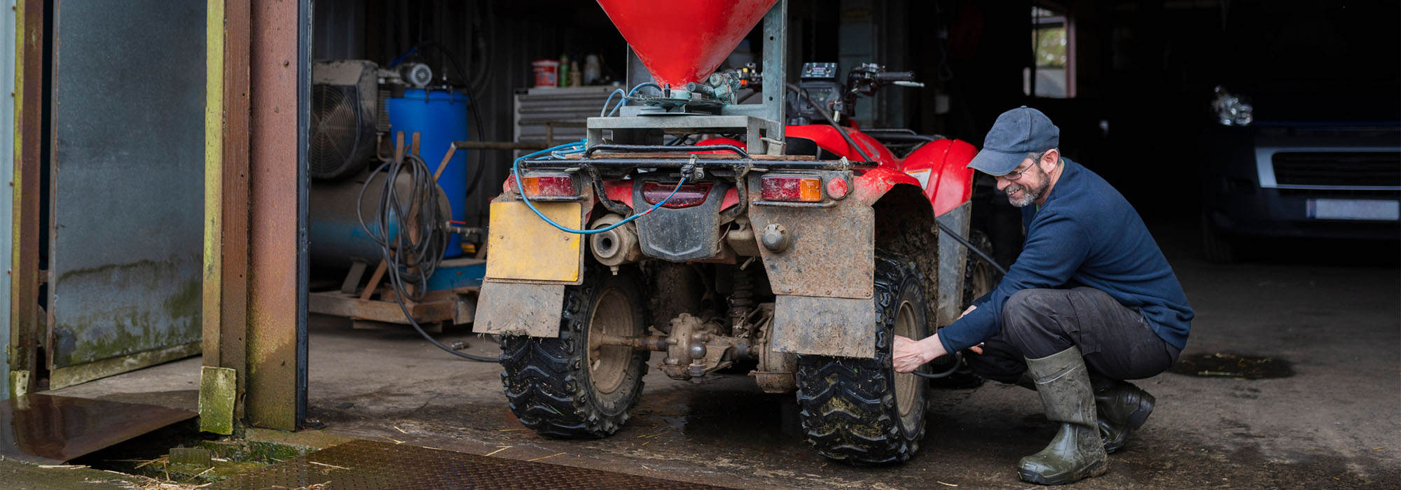 A man kneeling down next to a four wheeler